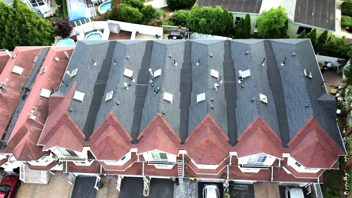 Aerial of rowhouse roof with new gray shingles beside red sections